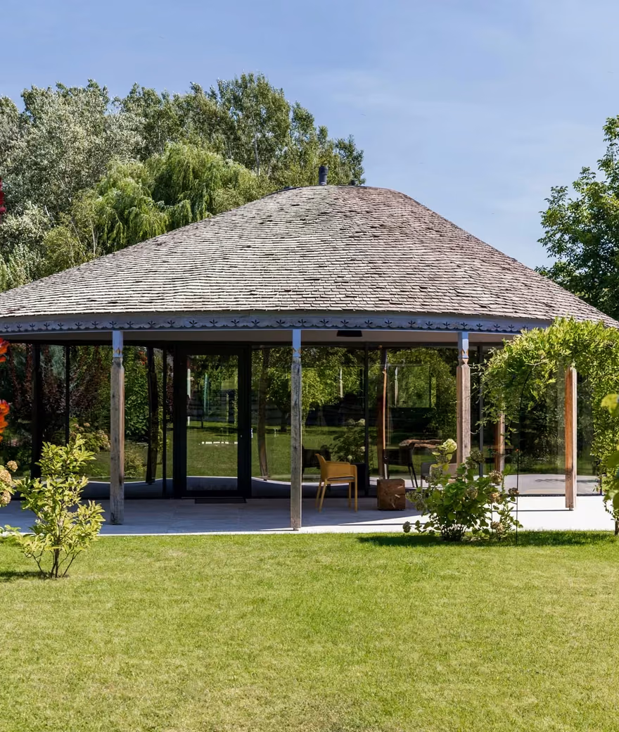 Garden view of a house with a rounded roof and expansive glass facades.