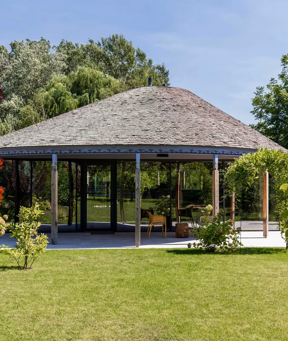 Garden view of a house with a rounded roof and expansive glass facades.