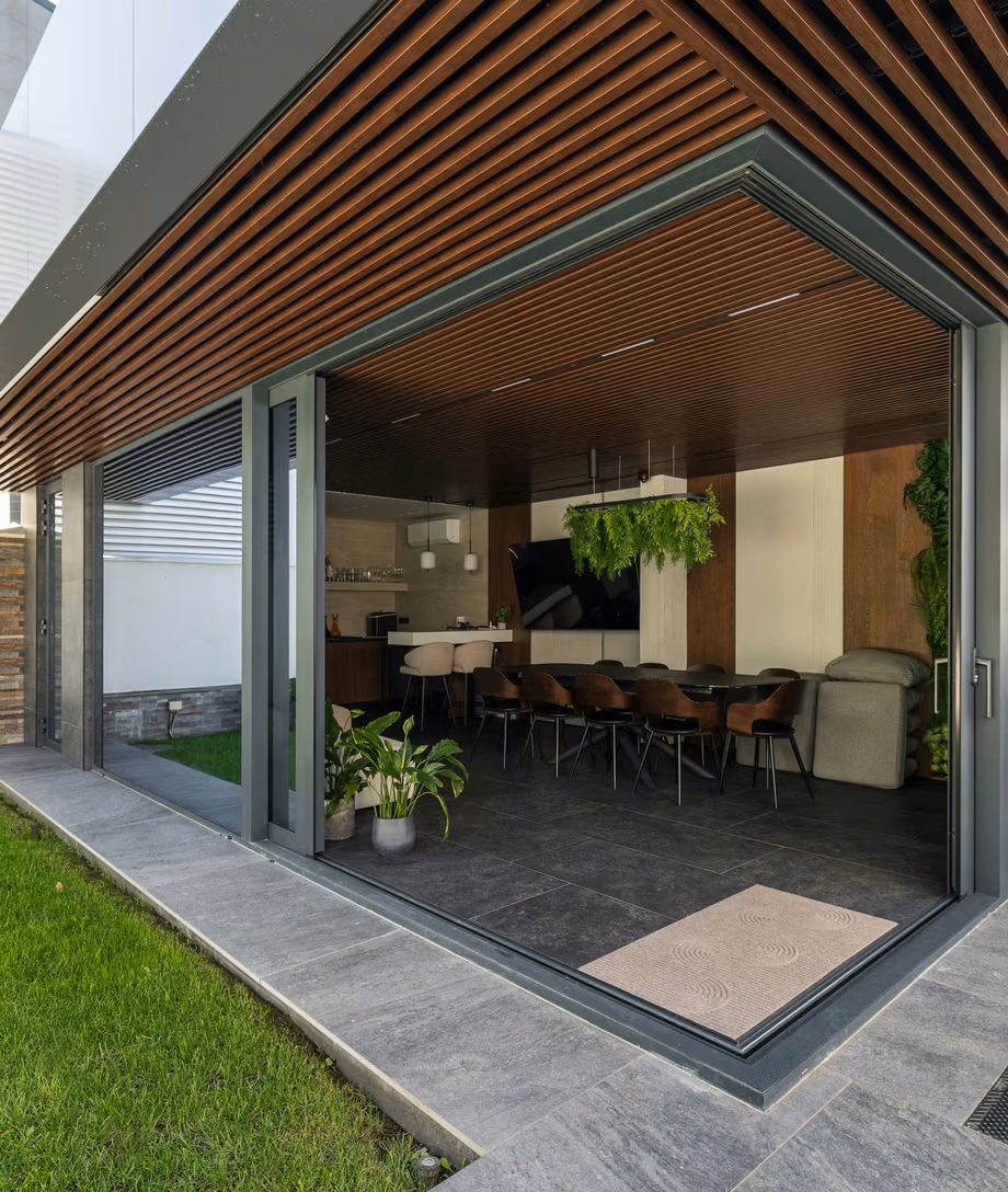 Contemporary terrace with panoramic glazing and dark aluminium frames.