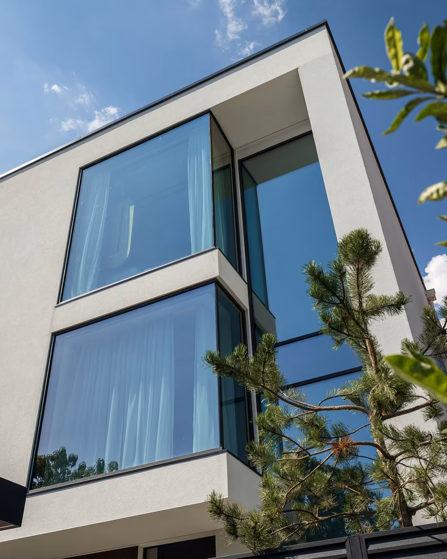 The view continues around the corner where glass surfaces meet without a visible mullion. Architecture quietly shaped by daylight and the landscape outside.