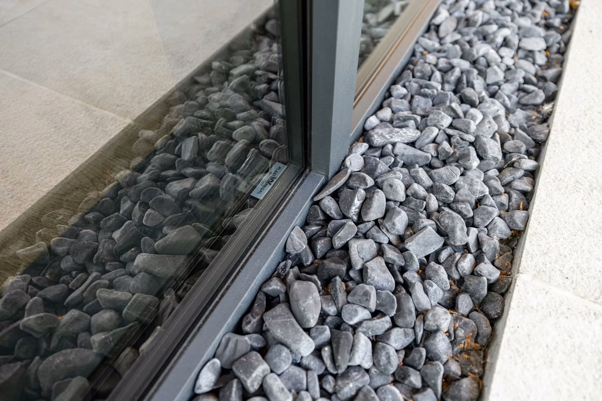 Lower glazing frame installed beside a strip of decorative gravel.