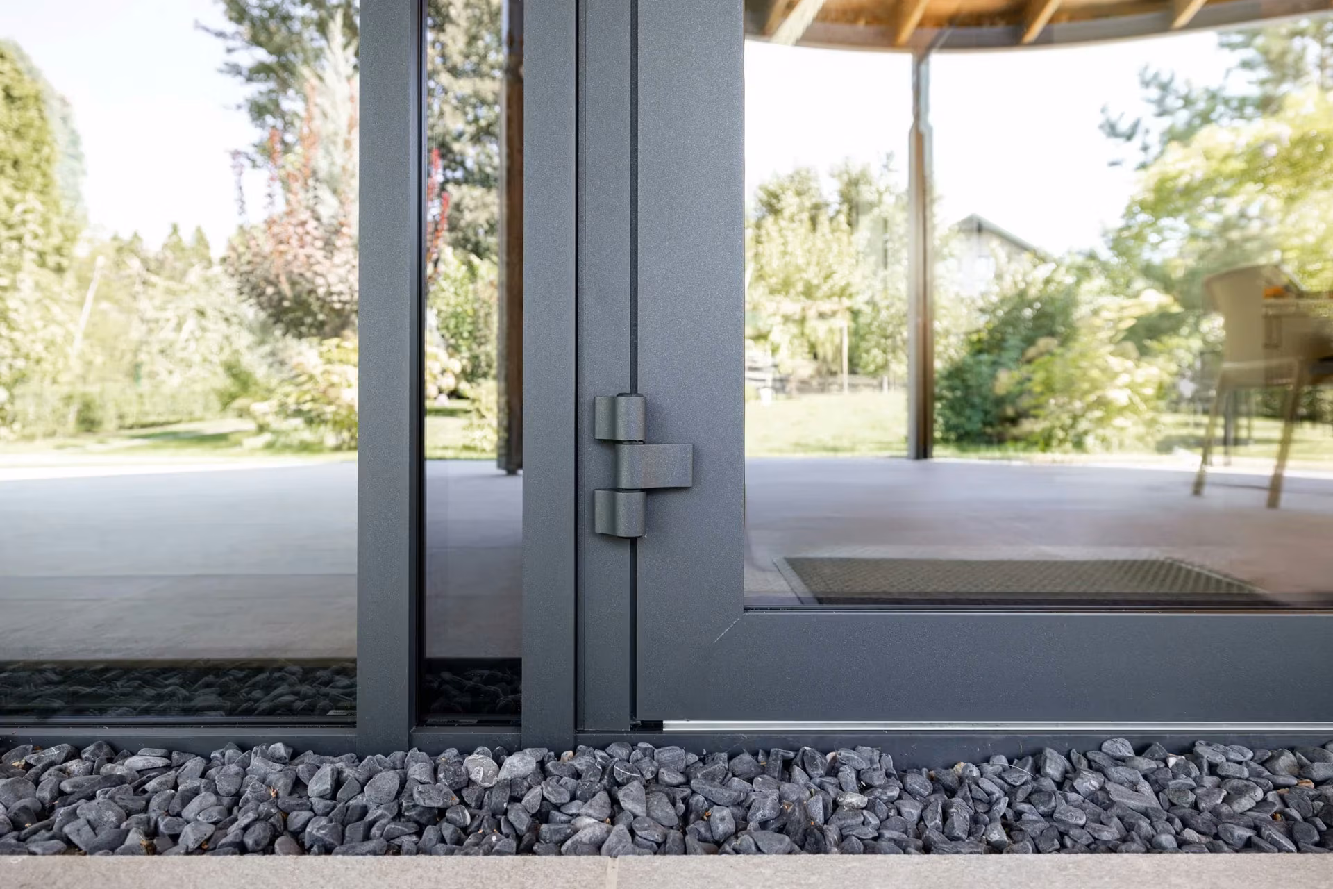 Exterior detail of an aluminium door hinge and threshold.