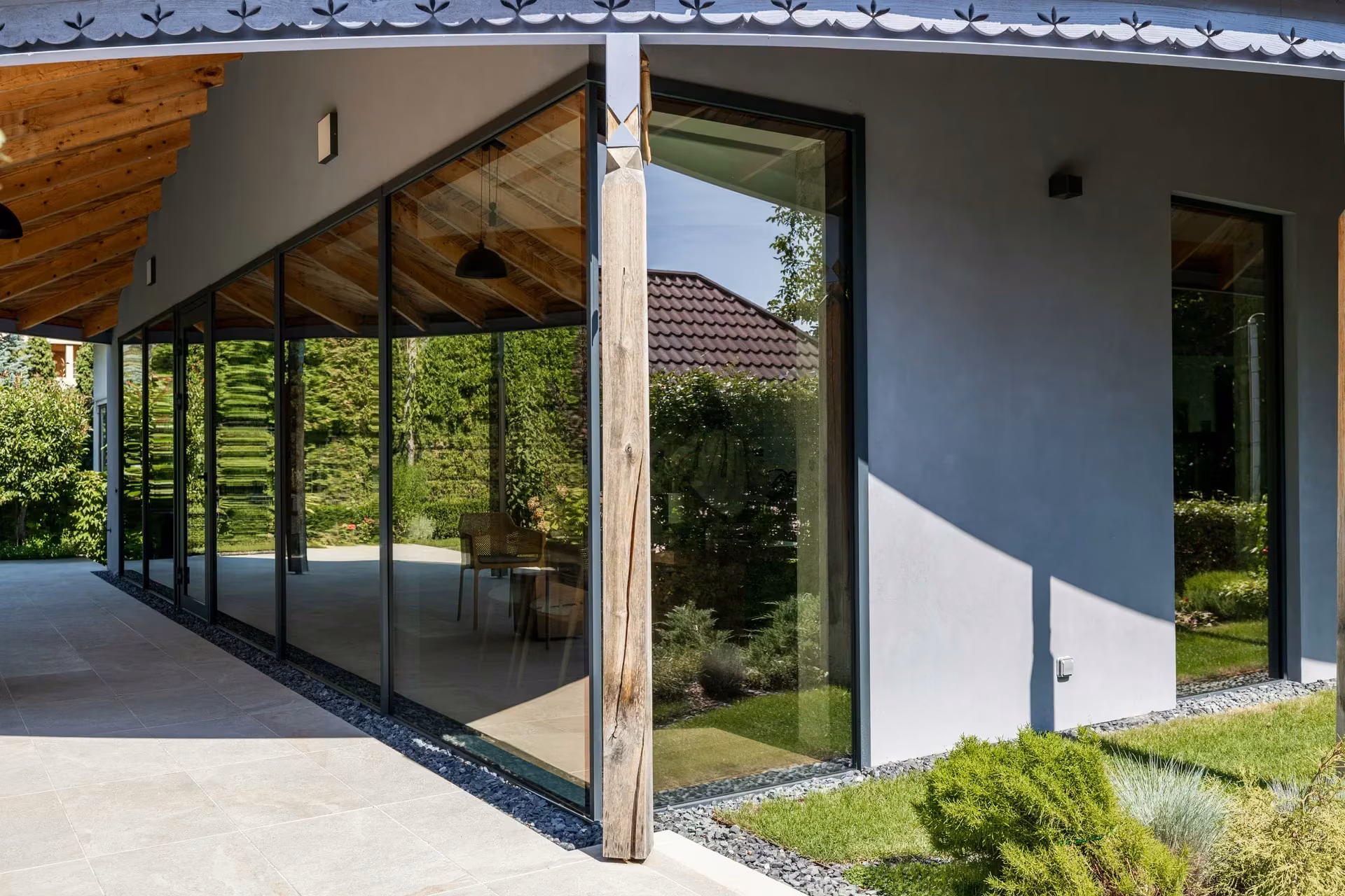 Side glazed facade with dark aluminium frames beside a grey exterior wall.
