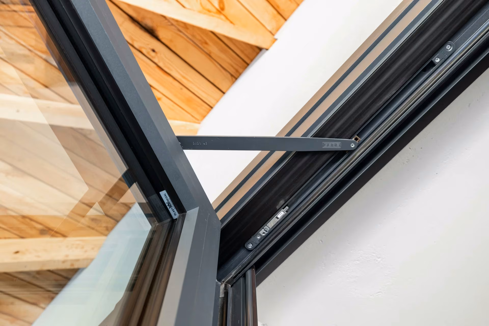 Detail of a metal operating arm mounted at the top of a glazed panel.