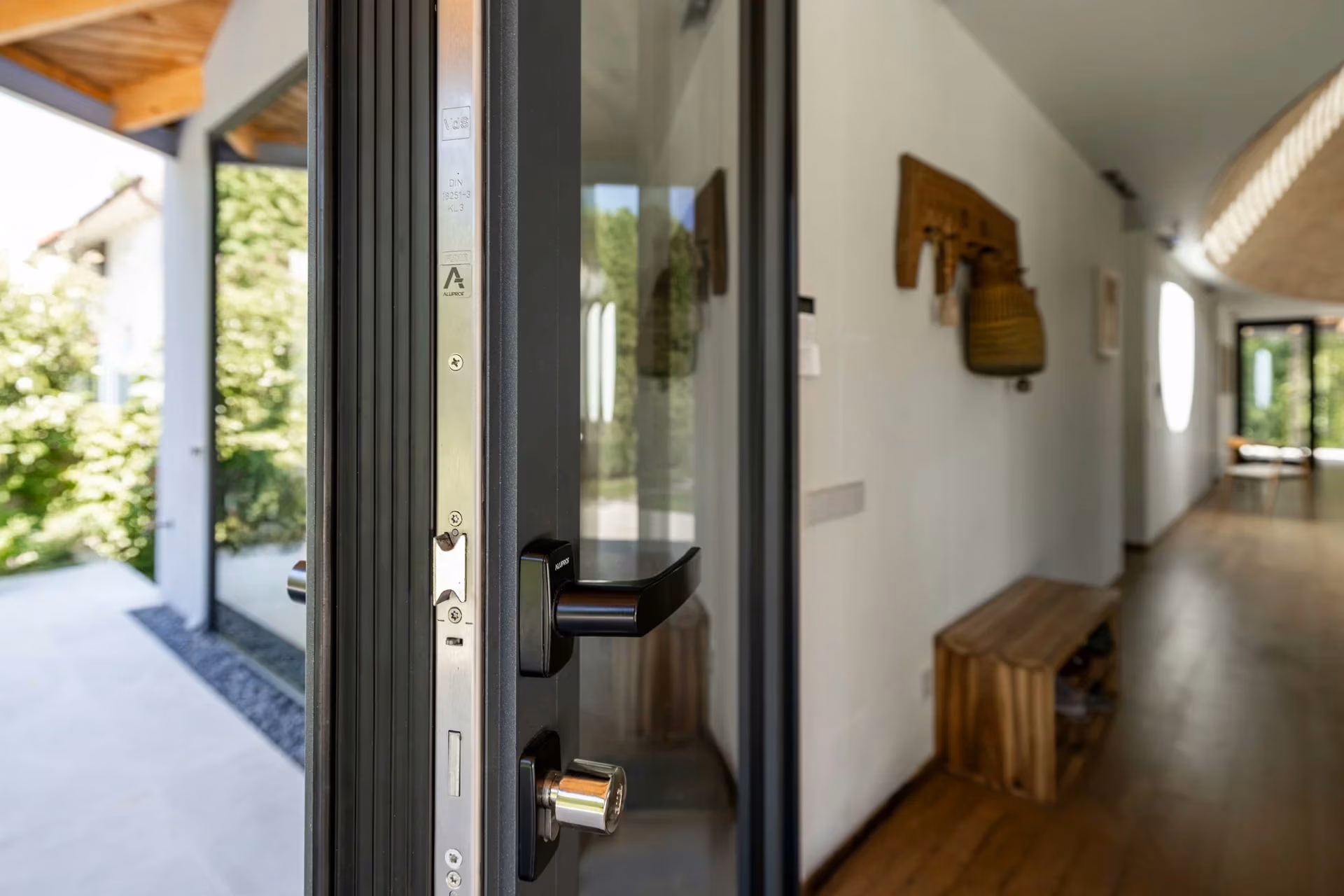 Open aluminium door with a black handle and visible locking mechanism.