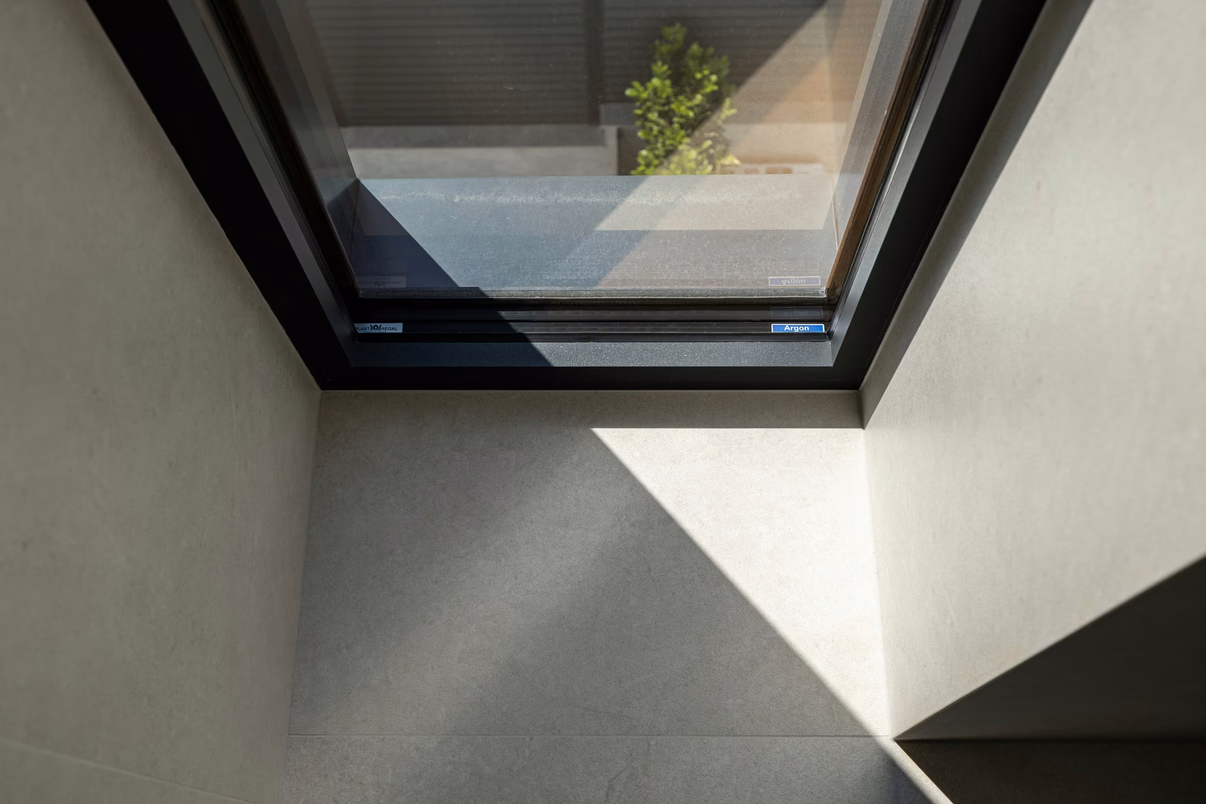 Detail of a corner window with dark frames and natural daylight.