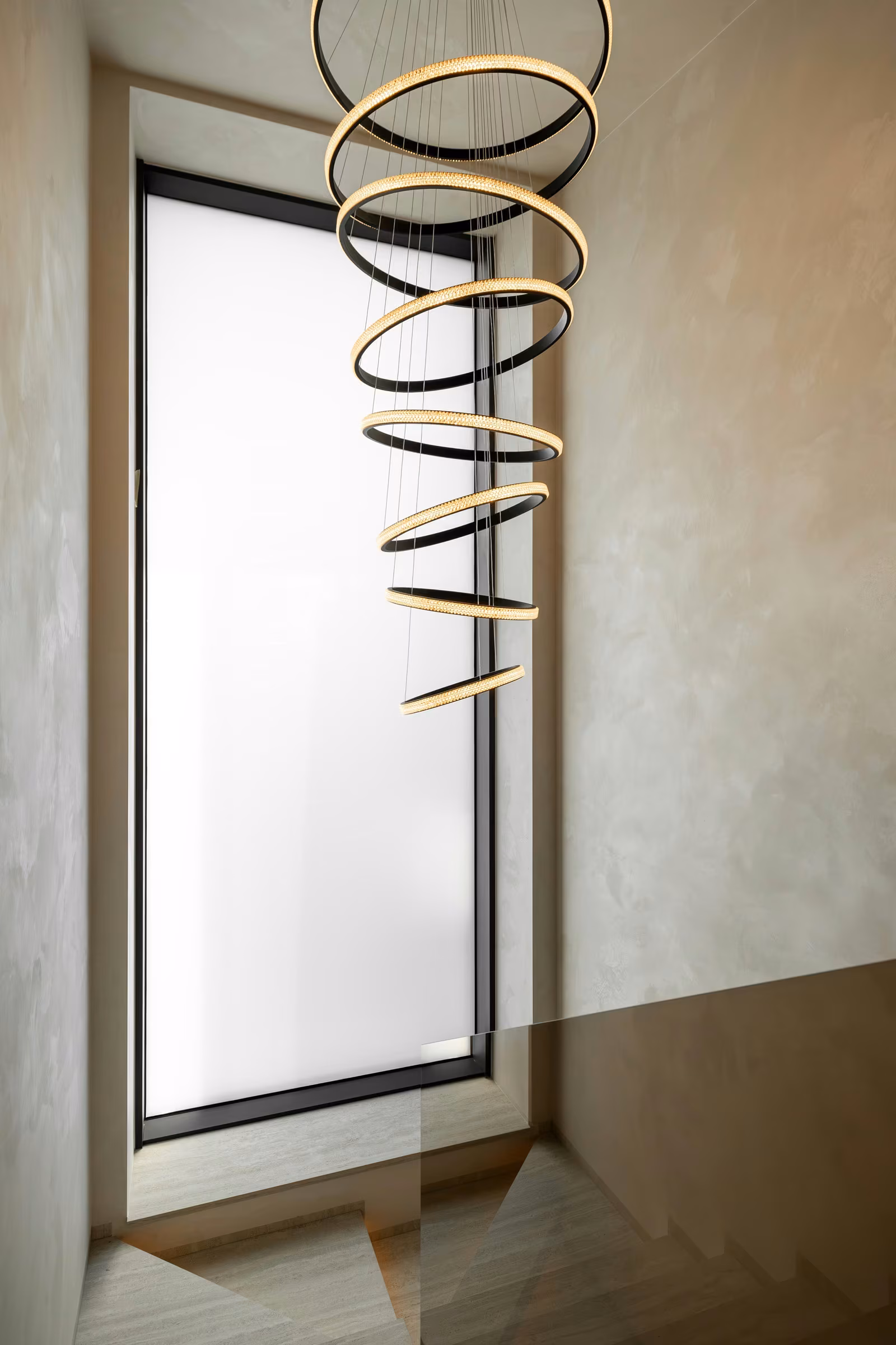 Tall window with translucent glass and a suspended spiral light fixture.
