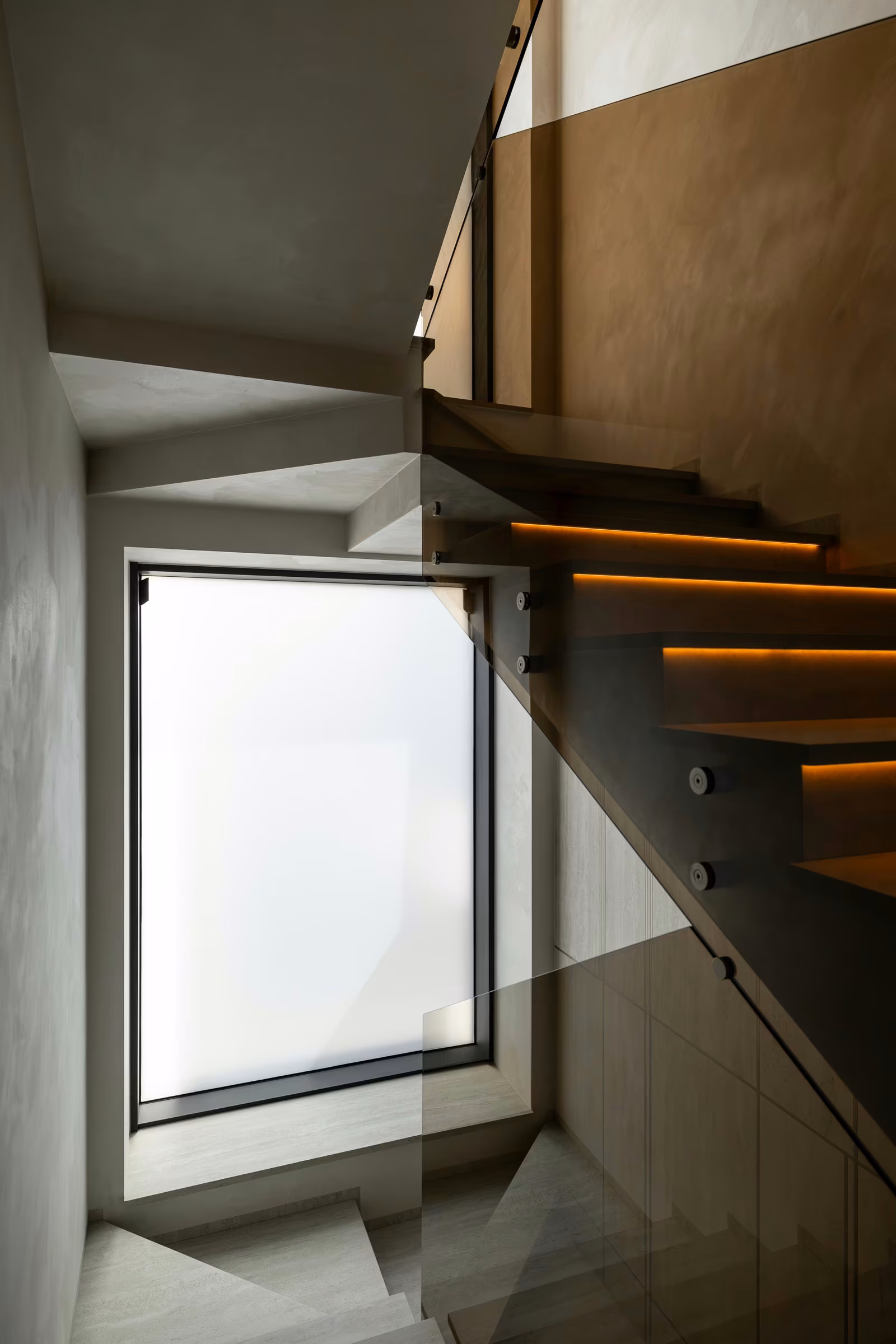 Frosted-looking window beside an interior staircase with a glass balustrade.