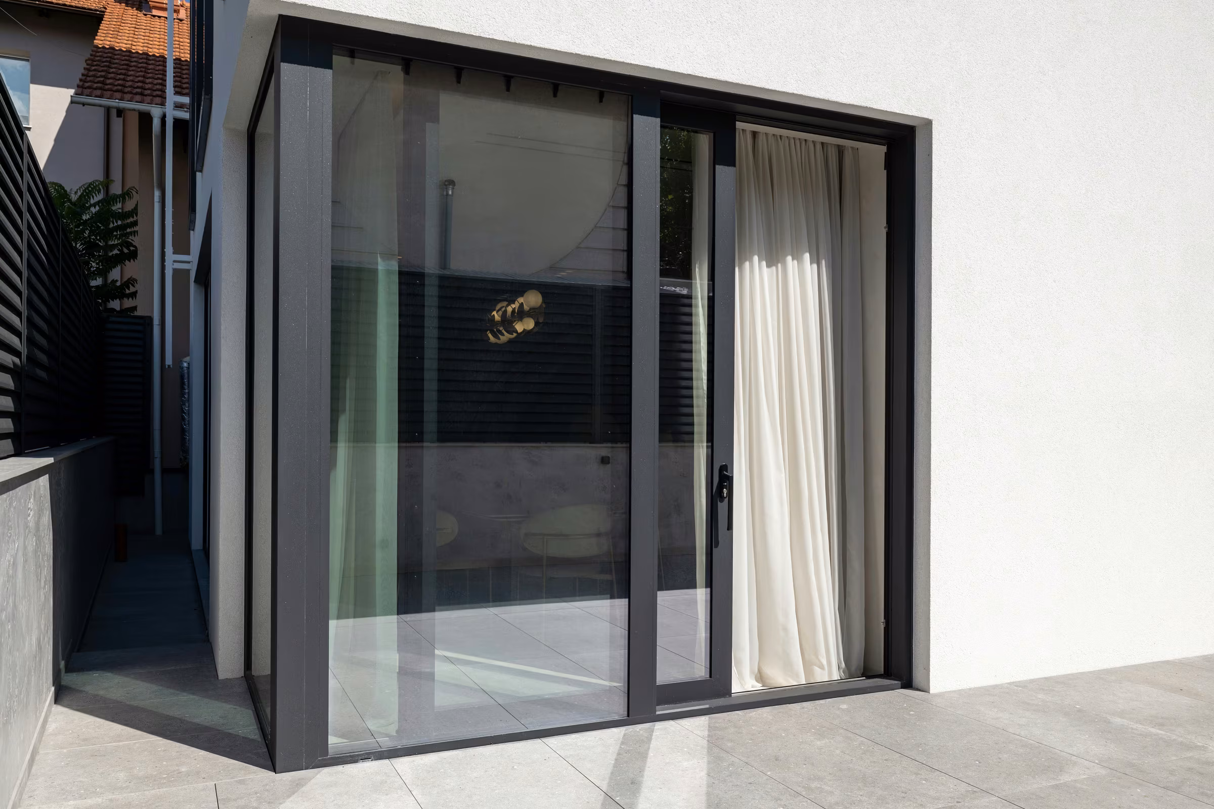 Panoramic aluminium sliding door overlooking a paved terrace.