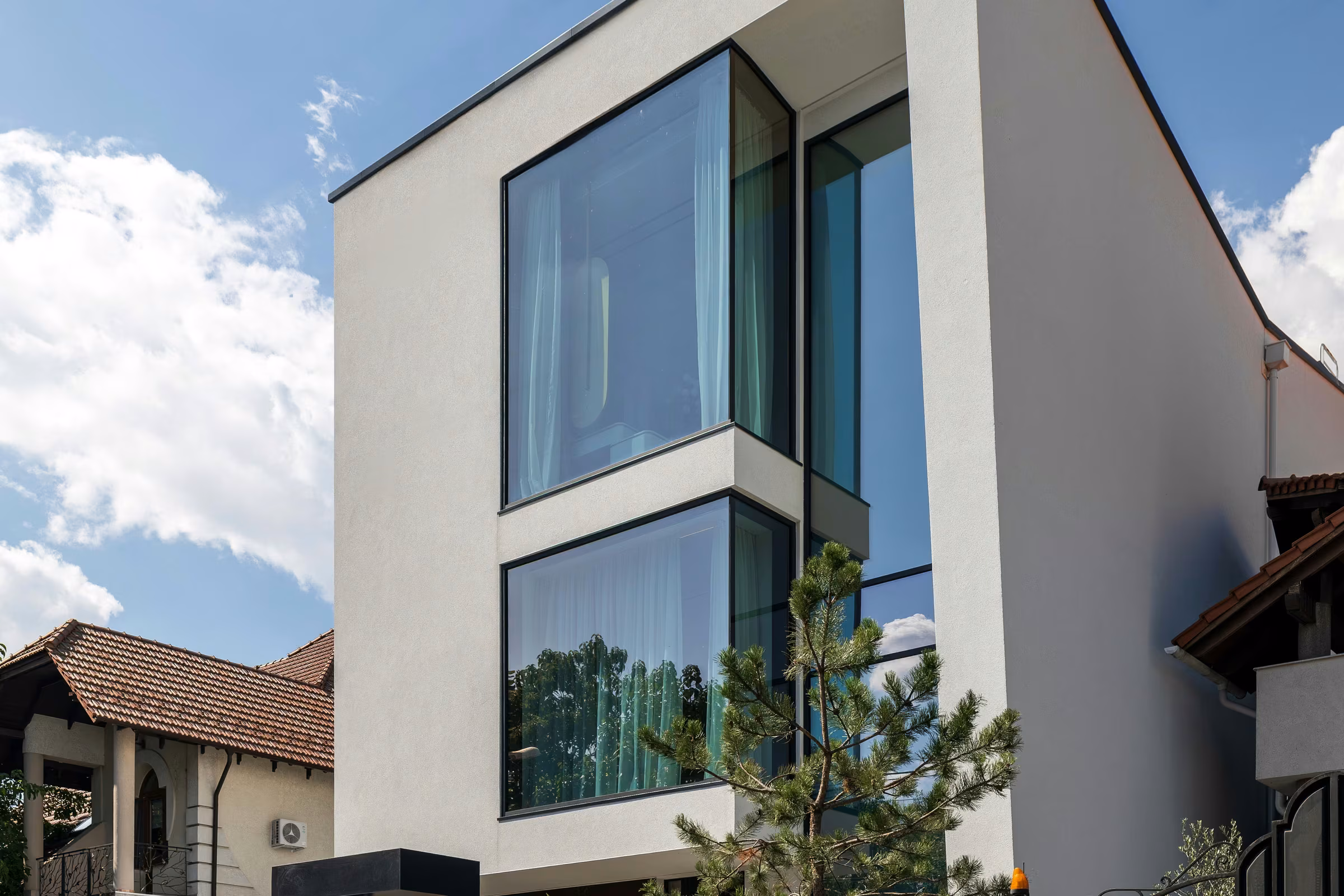 Low-angle view of the façade with tall glazing and glass corners.