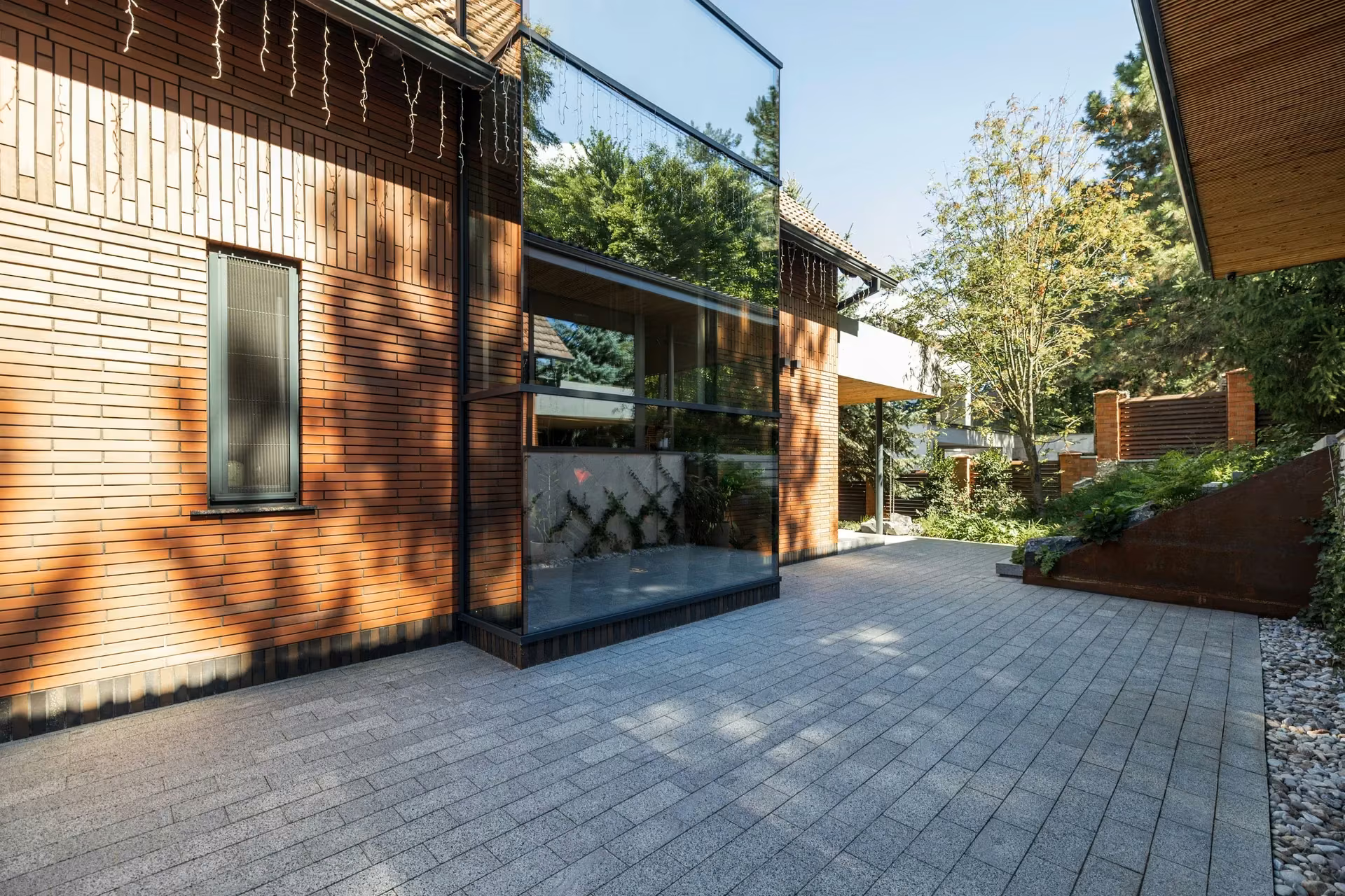 Paved side walkway along a brick façade with windows and surrounding greenery.