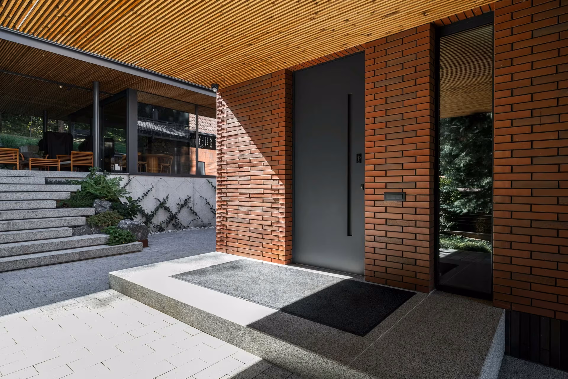 Entrance with a dark door, stone steps and an exterior timber ceiling.