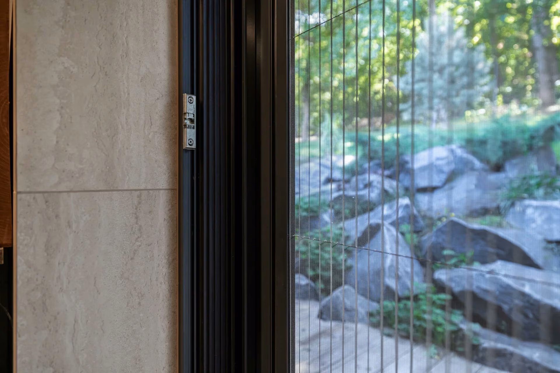 Close-up of an integrated pleated insect screen in a glazed opening, with greenery outside.