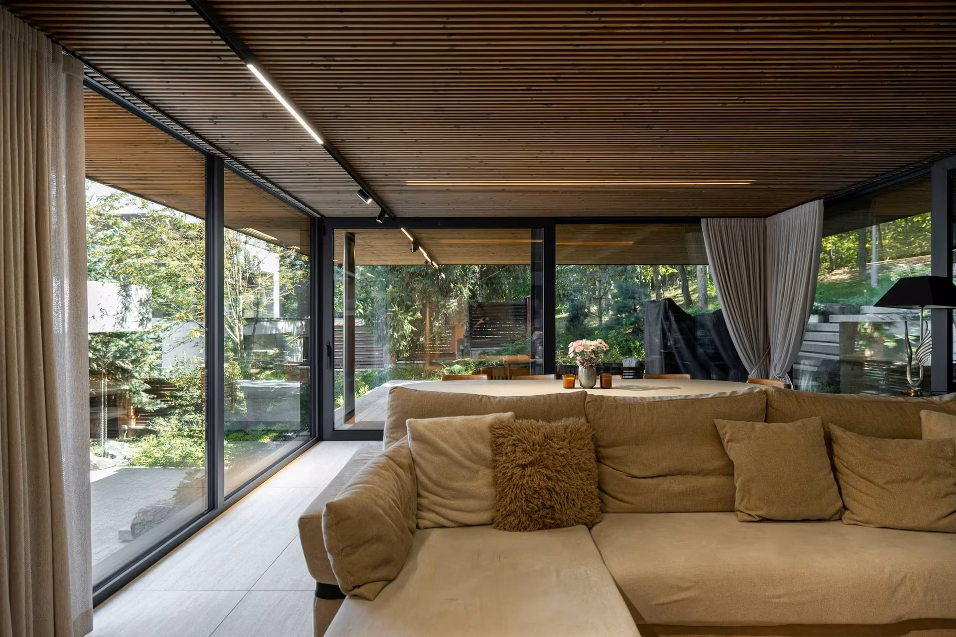 Sofa in a bright living room with glazing on two sides and greenery outdoors.