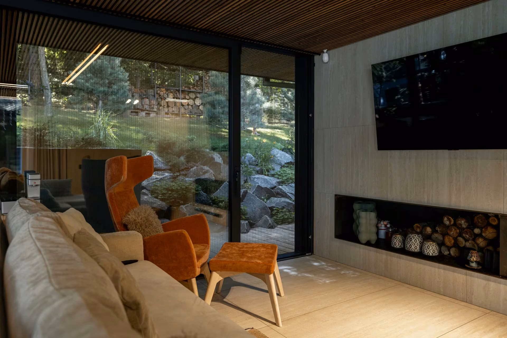 Contemporary living room with warm-toned armchairs, a fireplace and panoramic windows.