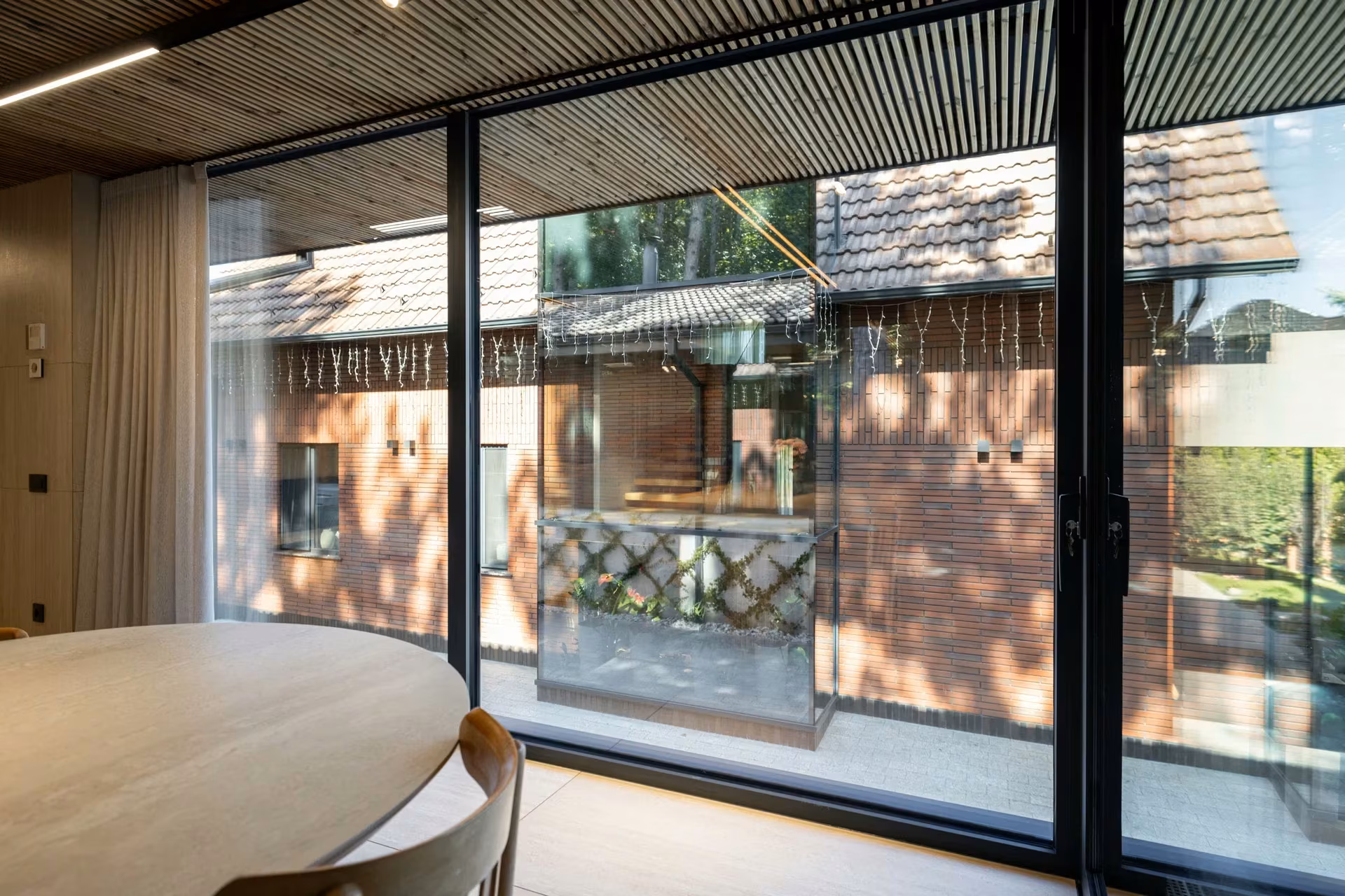 Dining area with panoramic glazed doors overlooking the terrace and brick façade.