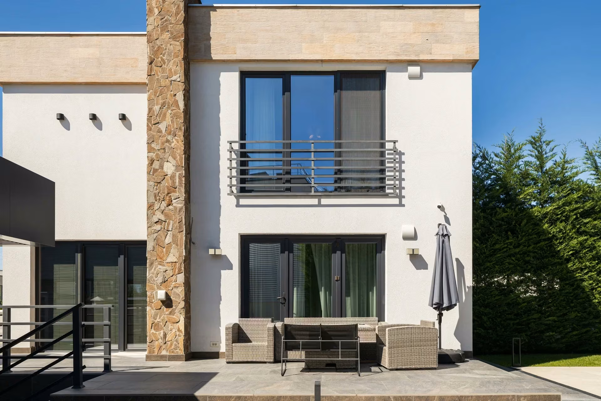 Front view of the home showing geometric volumes, textured cladding and windows with dark frames.
