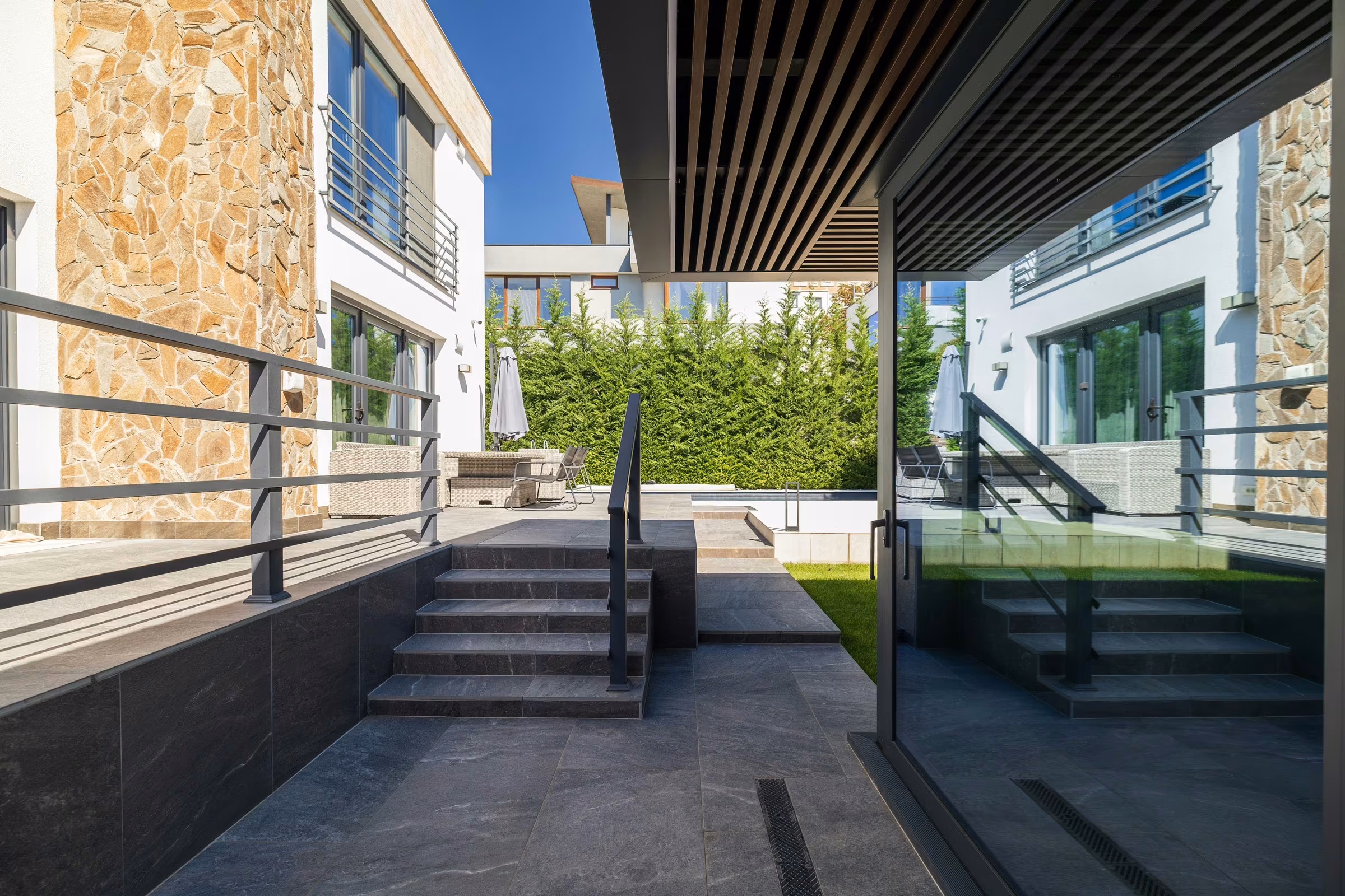 Side view of the terrace with dark aluminium frames and expansive glazing.