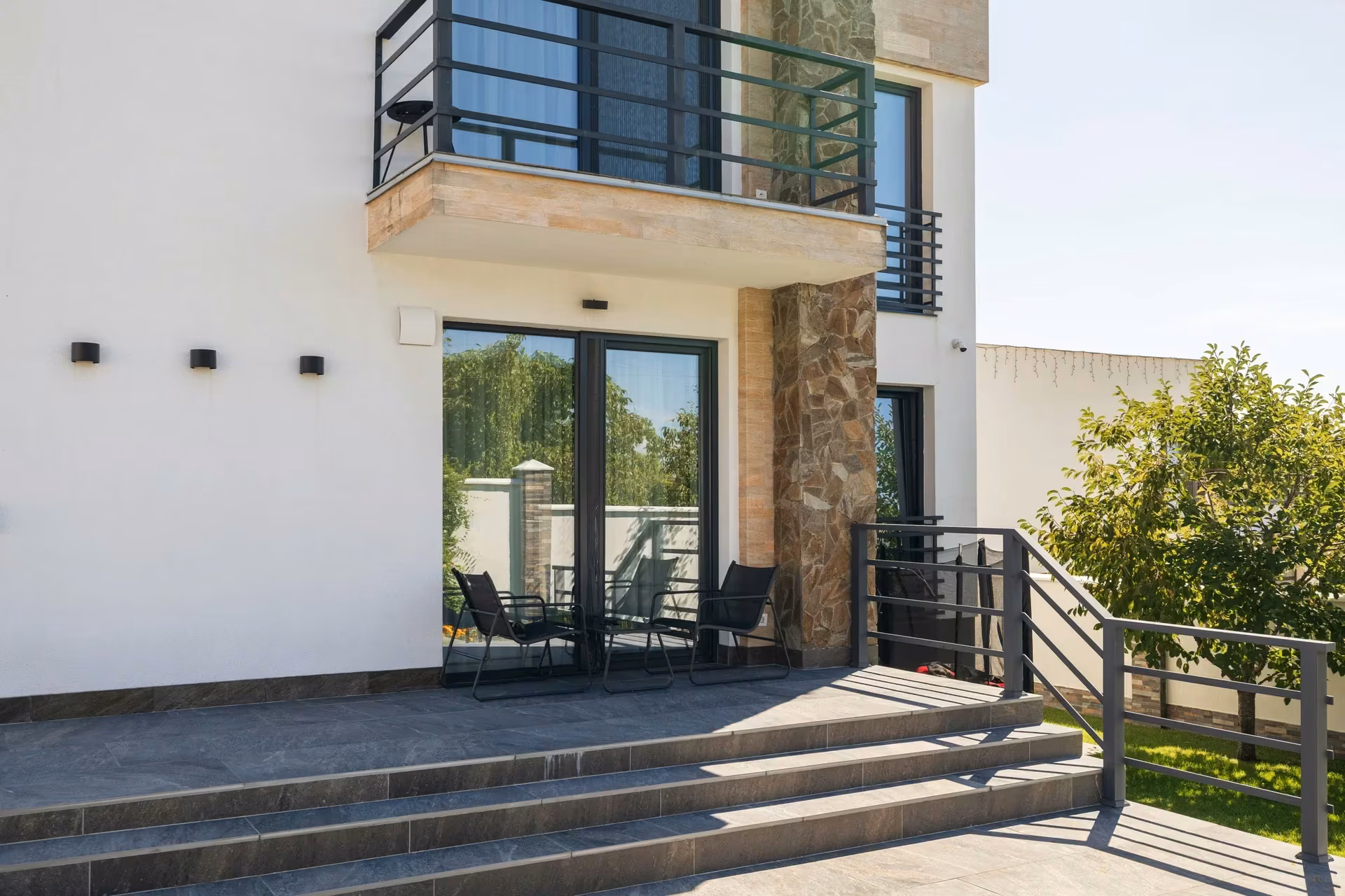 Angled view of the home with ground-floor glazing and windows integrated into the light-coloured facade.