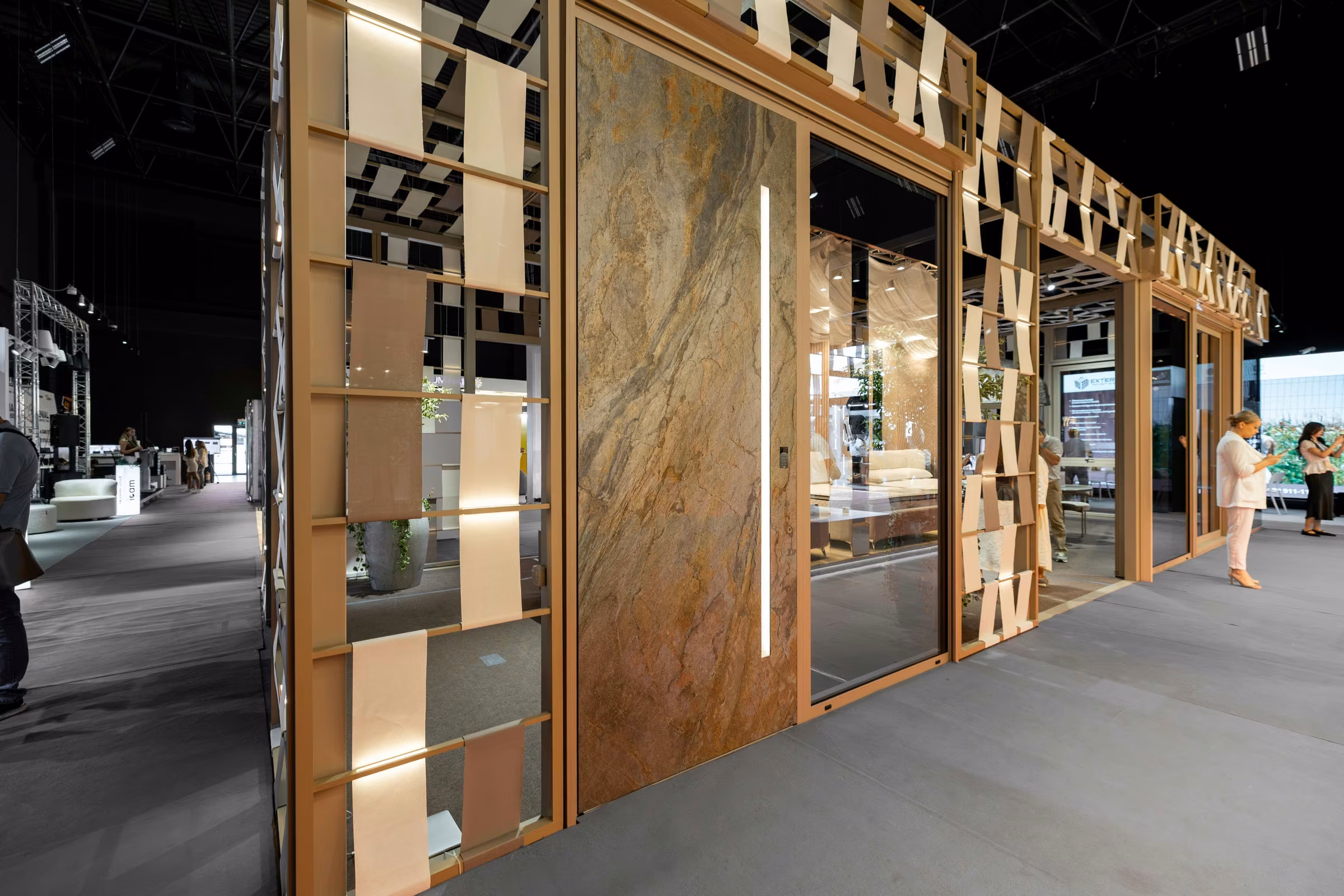 Side view of the Plastregal stand with a stone-look panel, glazing and a timber exhibition structure.