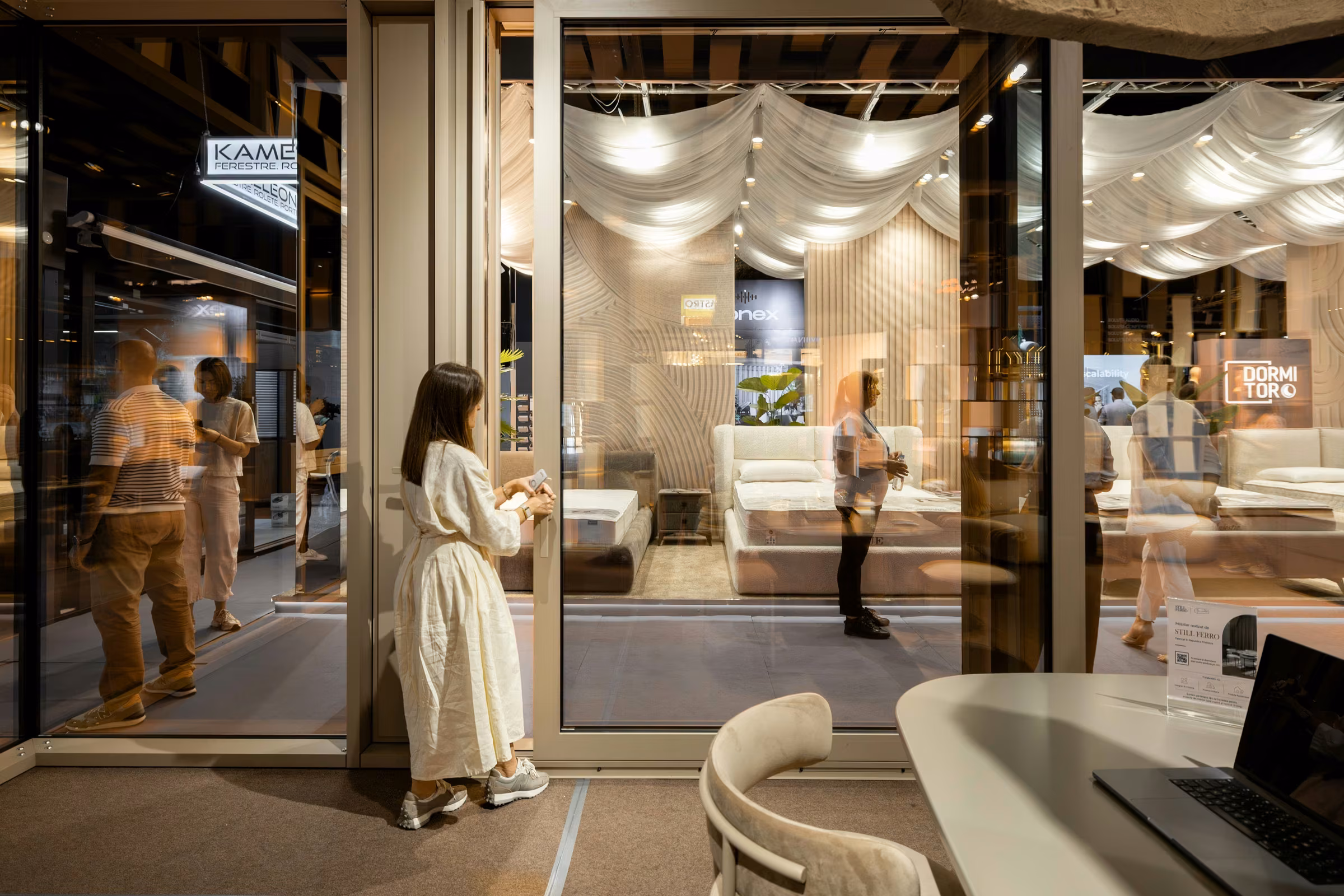 Panoramic glazing at the stand with visitors and the exhibition area visible through the glass.