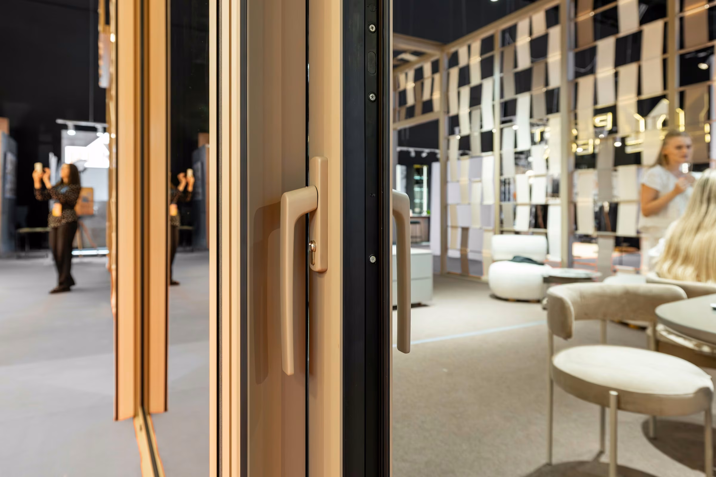 Handle detail of a glazed system with light-coloured aluminium frames.