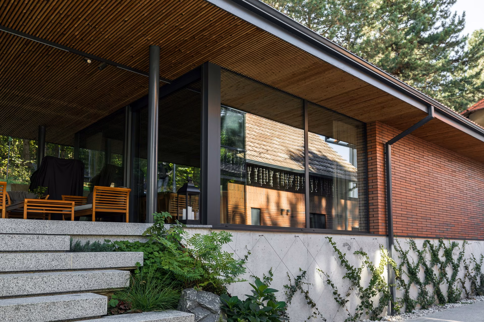 A home where panoramic glazing opens the rooms to the garden, while brick, timber and carefully resolved details shape a warm, balanced architectural character.