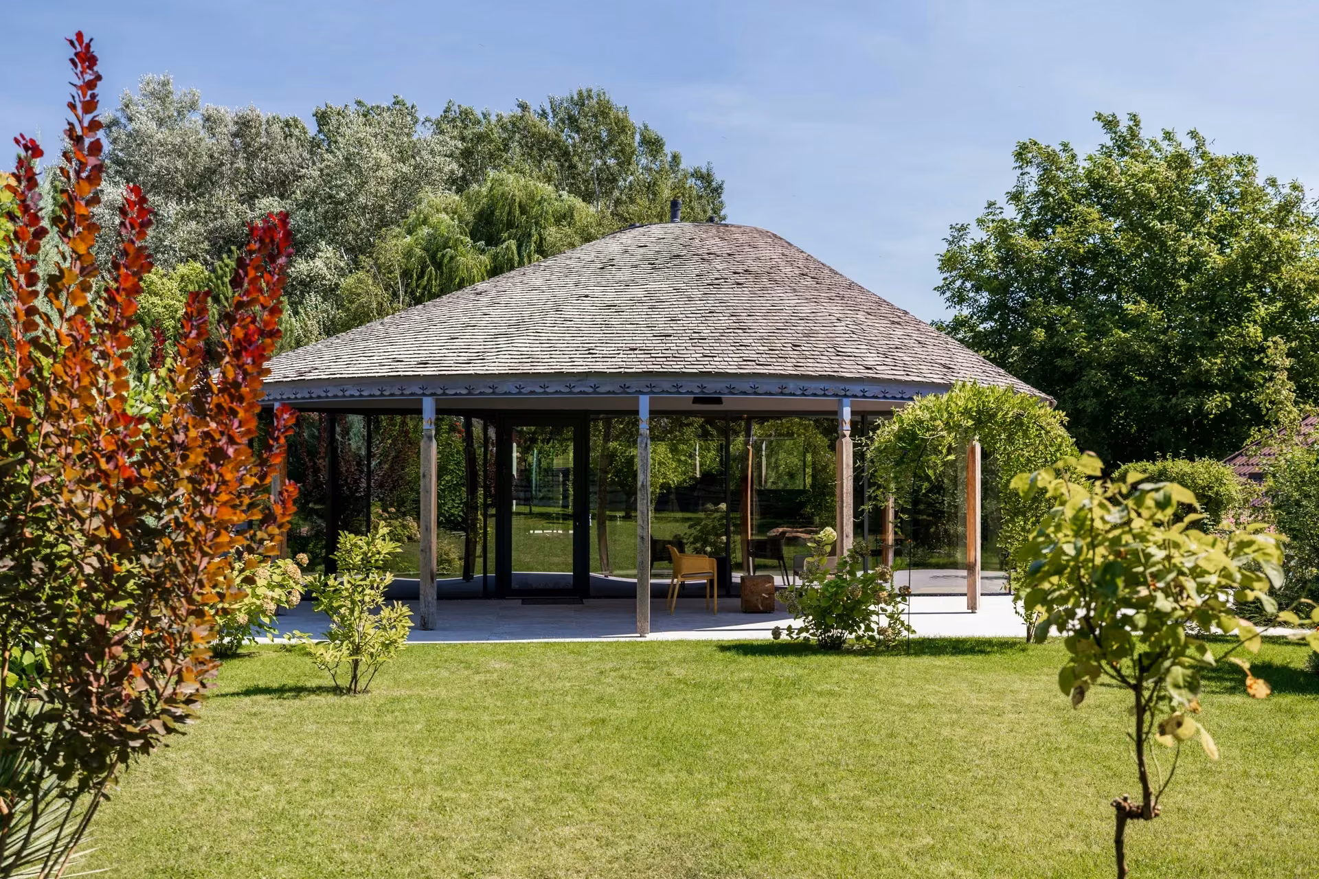 Garden view of a house with a rounded roof and expansive glass facades.